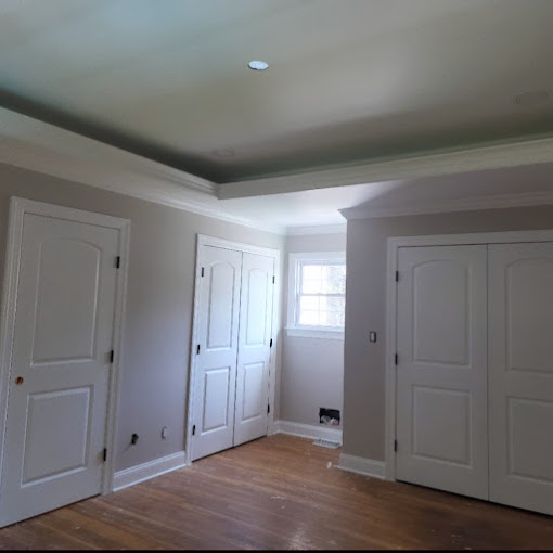 An empty room with white doors and a hard wood floor