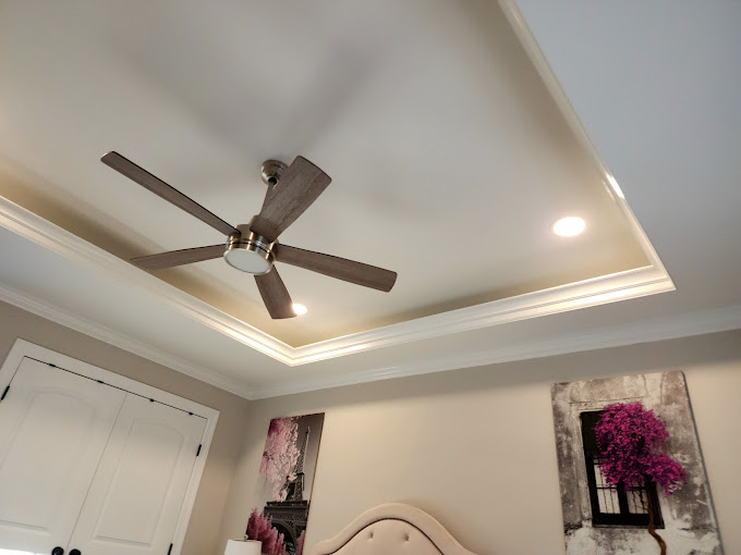 A bedroom with a ceiling fan and a bed