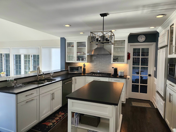 A kitchen with white cabinets and black counter tops